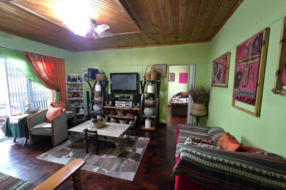 A living room featuring traditional parquet flooring and a timber tongue and groove ceiling, with access to an outdoor area via a security gate.