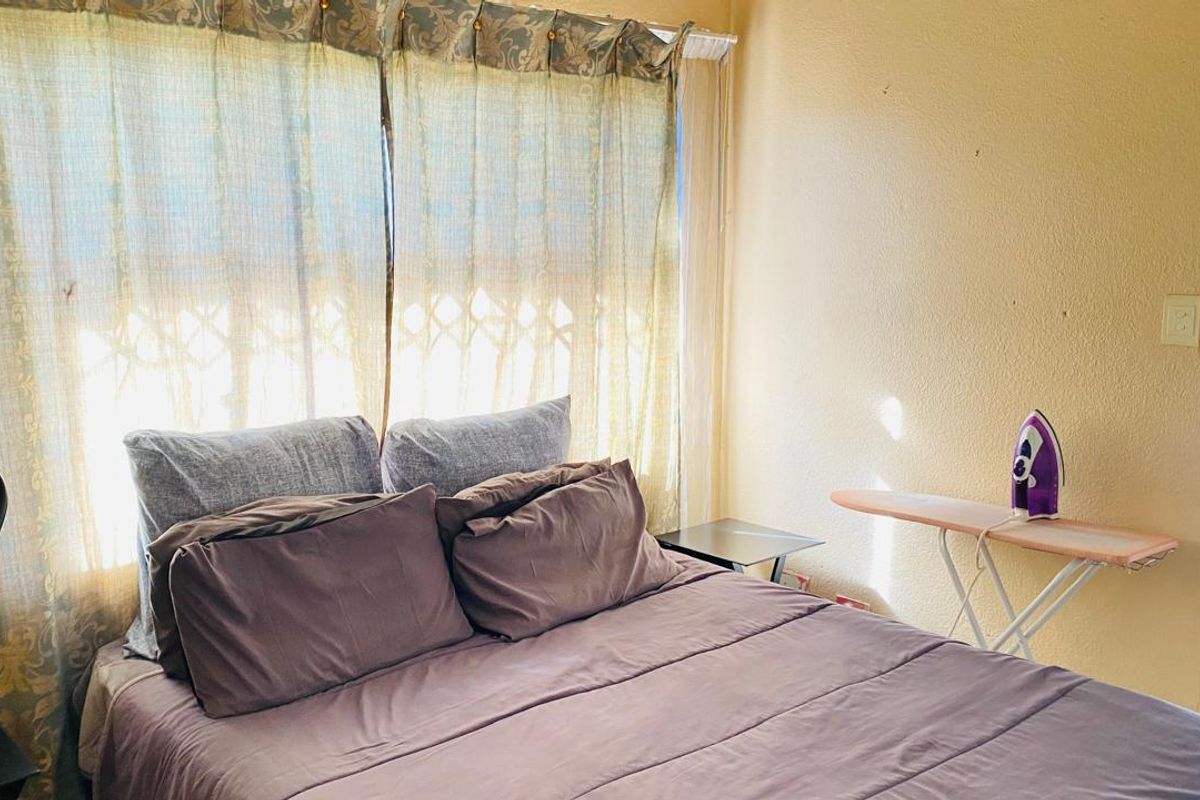 A bedroom featuring a window with installed curtain rods and textured wall finishes.