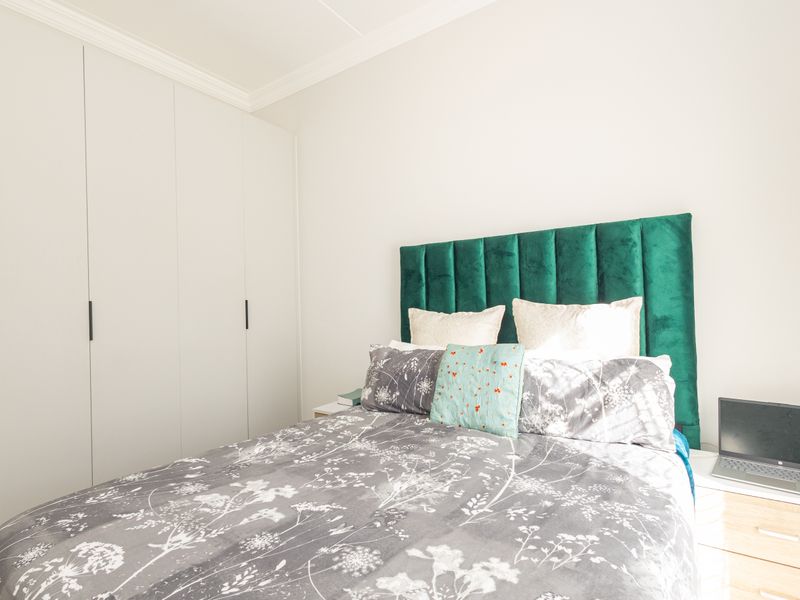 A well-maintained bedroom featuring floor-to-ceiling built-in cupboards and classic crown molding, providing ample storage and a clean, neutral aesthetic.