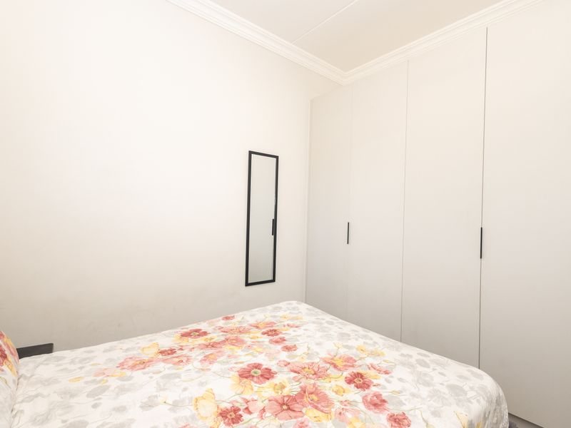 A clean bedroom featuring floor-to-ceiling built-in cupboards and decorative ceiling cornicing.