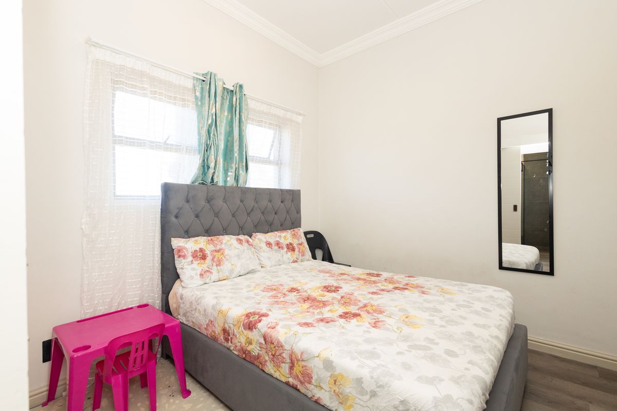 A functional bedroom featuring laminate flooring and decorative ceiling coving, providing a neutral base for personalization.