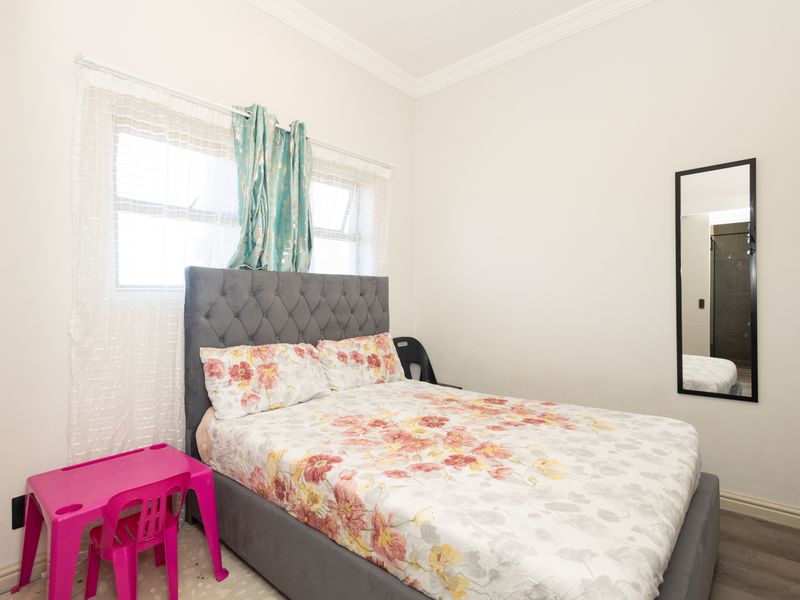 A functional bedroom featuring laminate flooring and decorative ceiling coving, providing a neutral base for personalization.