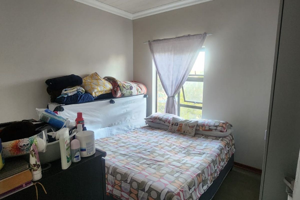 A functional bedroom featuring a built-in cupboard and a window, providing natural light and essential storage space.