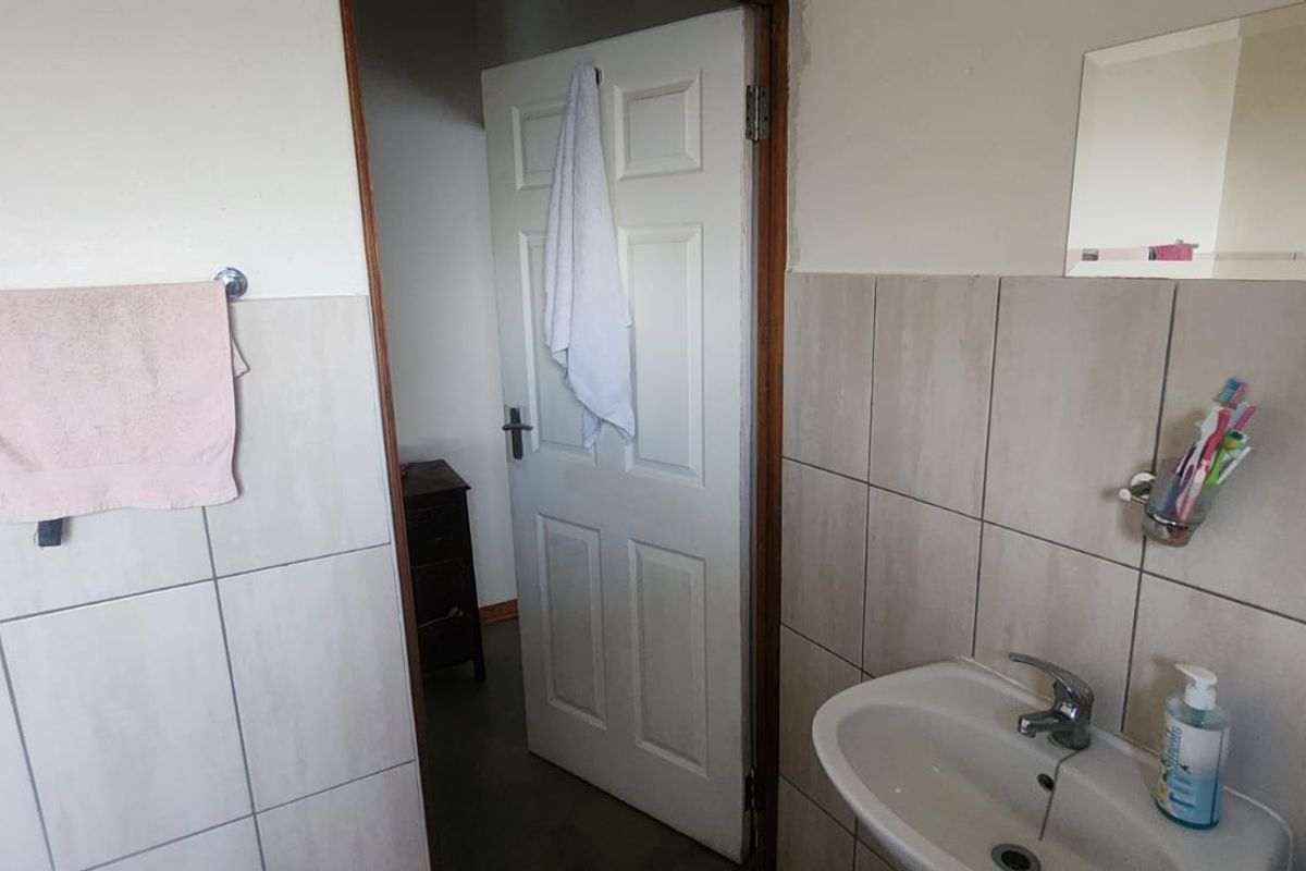 A functional bathroom featuring a wall-mounted basin with chrome tapware and neutral ceramic wall tiling.