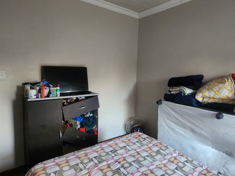 A bedroom featuring neutral wall finishes and coving, with an adjacent hallway visible through the doorway.