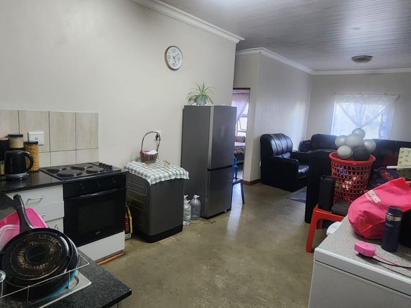 Open-plan kitchen and living area featuring built-in cabinetry, granite countertops, and an electric stove, with direct access to the adjacent living space.