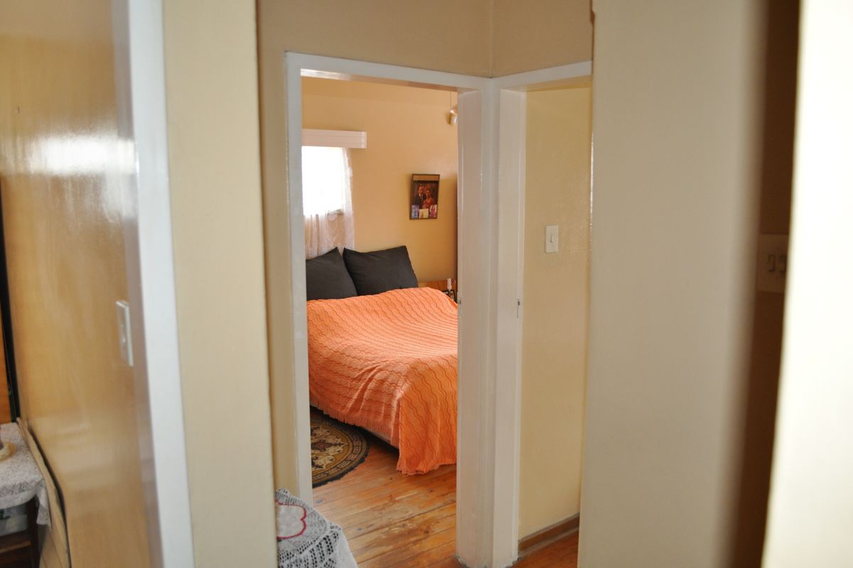 A view through a doorway into a bedroom featuring timber flooring and neutral wall finishes.