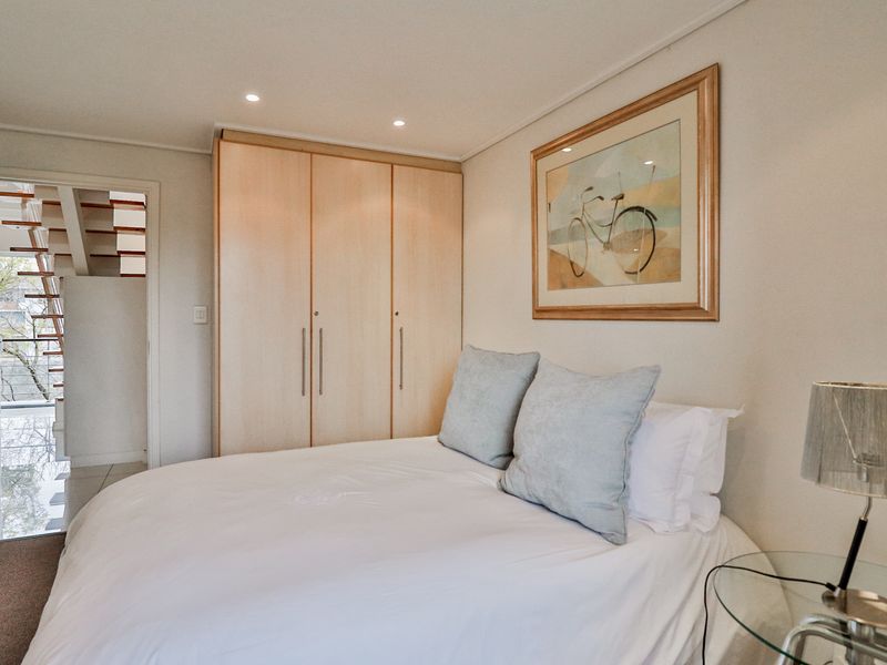 A well-maintained bedroom featuring a light wood built-in wardrobe and recessed ceiling lighting, offering a clean and functional living space.