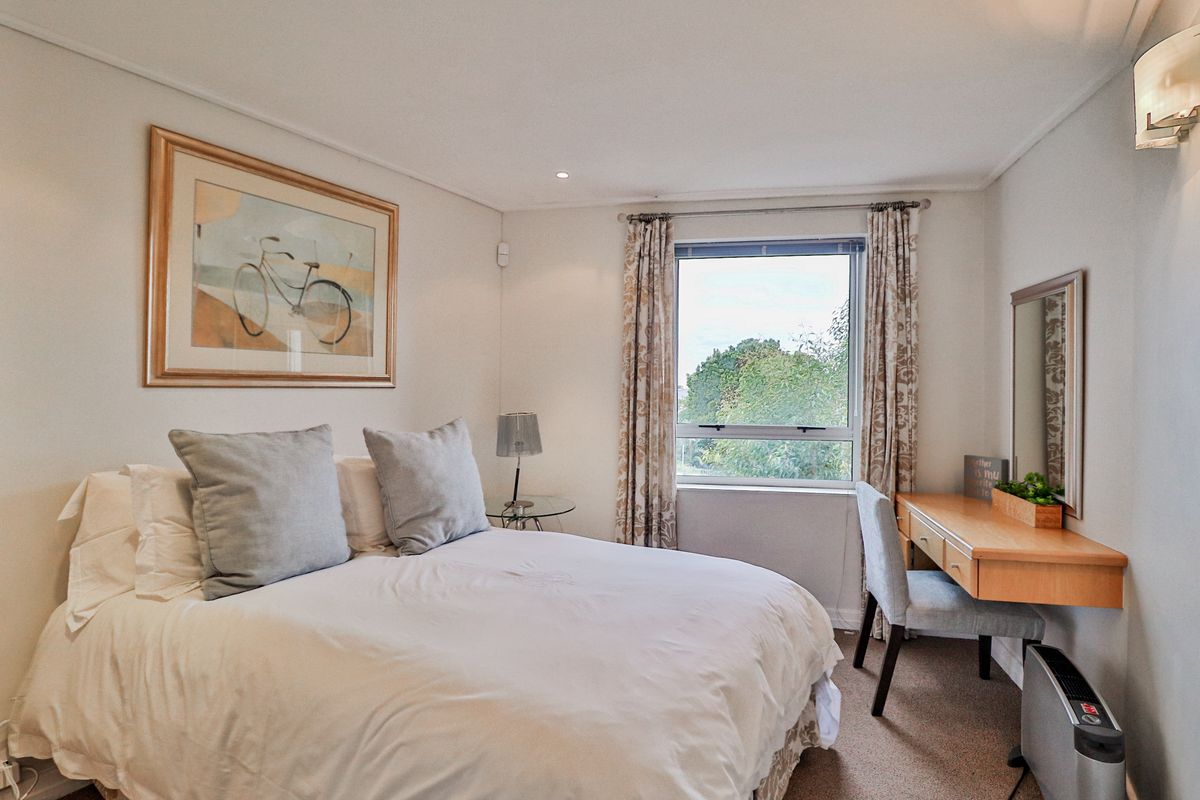 A well-maintained bedroom featuring neutral walls, carpeted flooring, recessed lighting, and a window providing natural light.