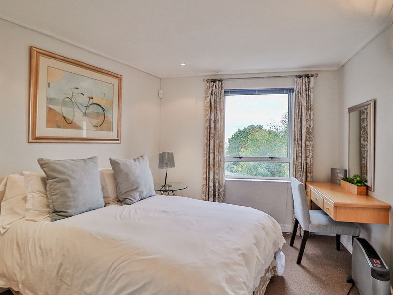 A well-maintained bedroom featuring neutral walls, carpeted flooring, recessed lighting, and a window providing natural light.