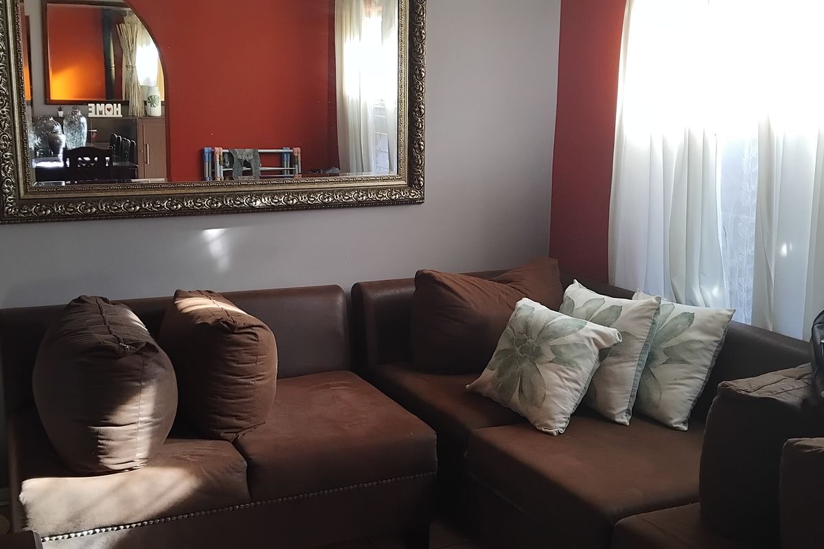 A living room area featuring a neutral wall color with a bold red accent wall and natural light from the window.