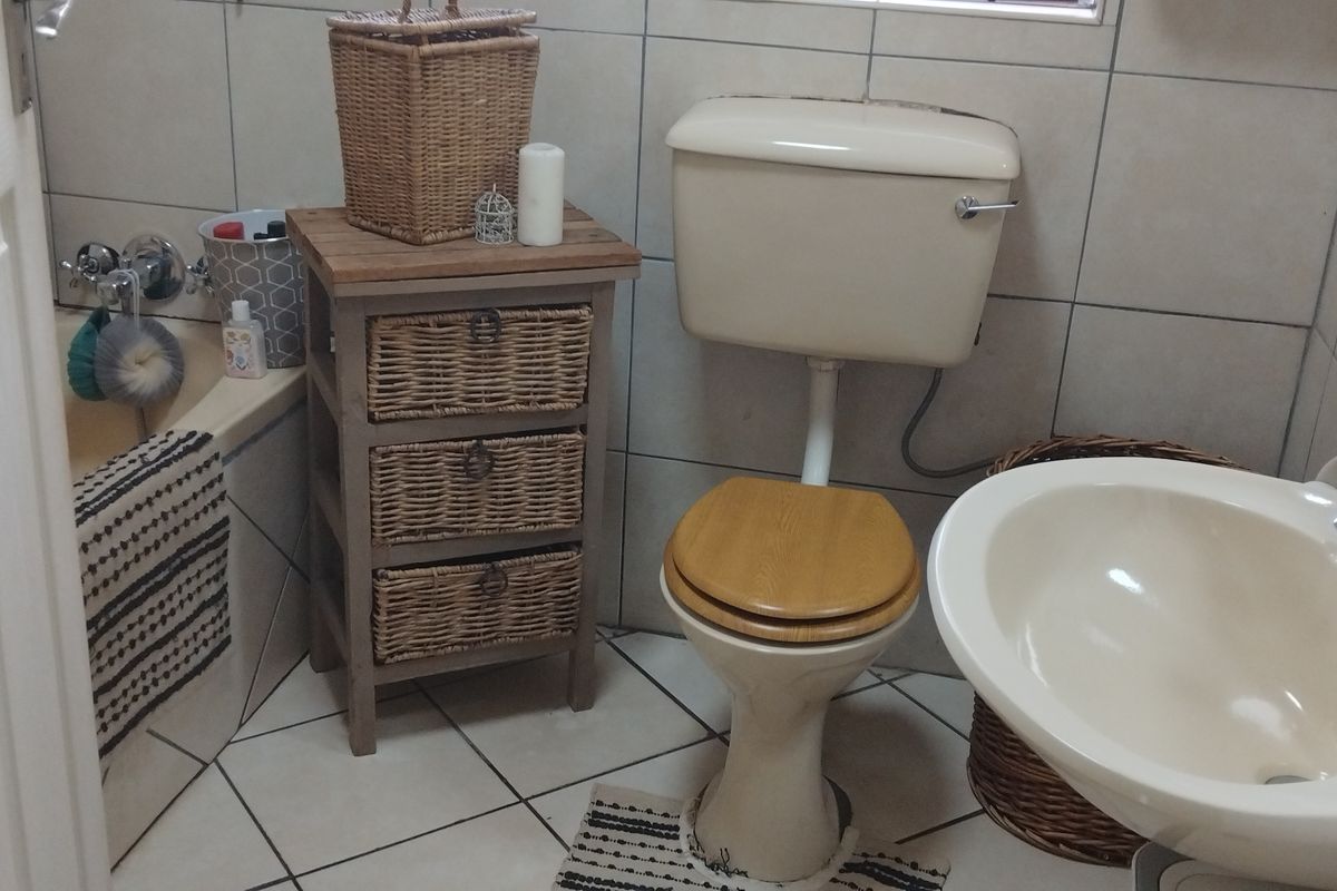 A compact bathroom featuring dated cream-colored sanitaryware, ceramic wall and floor tiles, and a standard bathtub with chrome fixtures.
