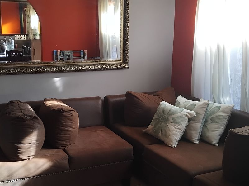 A living room area featuring a neutral wall color with a bold red accent wall and natural light from the window.