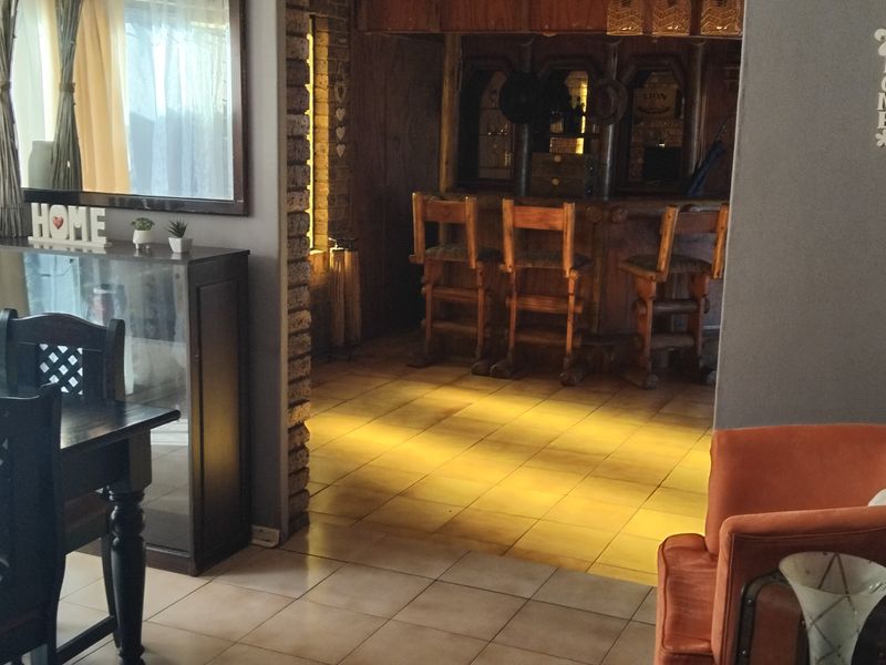A dedicated bar area featuring a built-in counter, tiled flooring, and rustic exposed brick accents, providing a distinct space for entertainment.