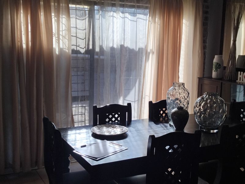Dining room featuring exposed brick walls and a sliding glass door with security gate, providing natural light to the space.
