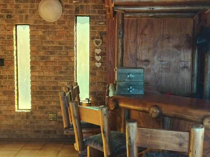 A rustic-style home bar featuring exposed brick walls, timber paneling, and a built-in wooden bar counter with matching stools.