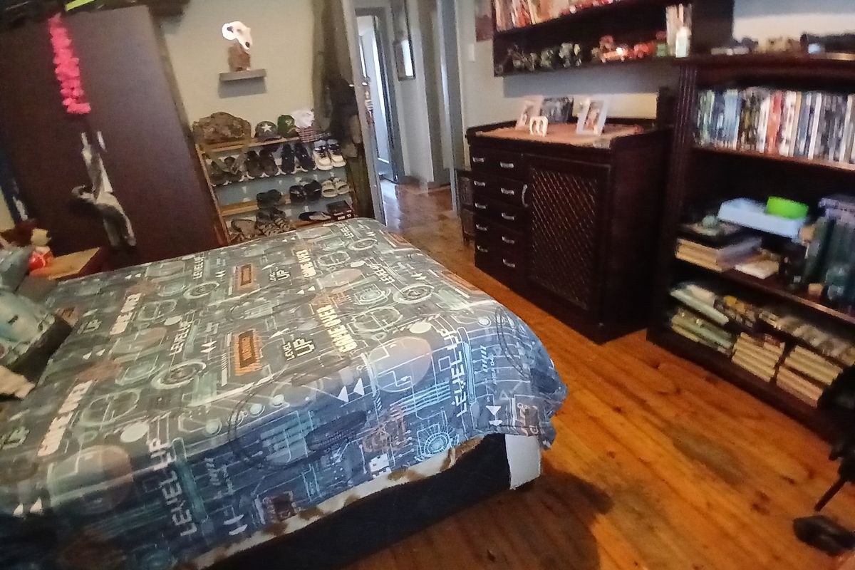A bedroom featuring timber flooring and access to an adjoining hallway.