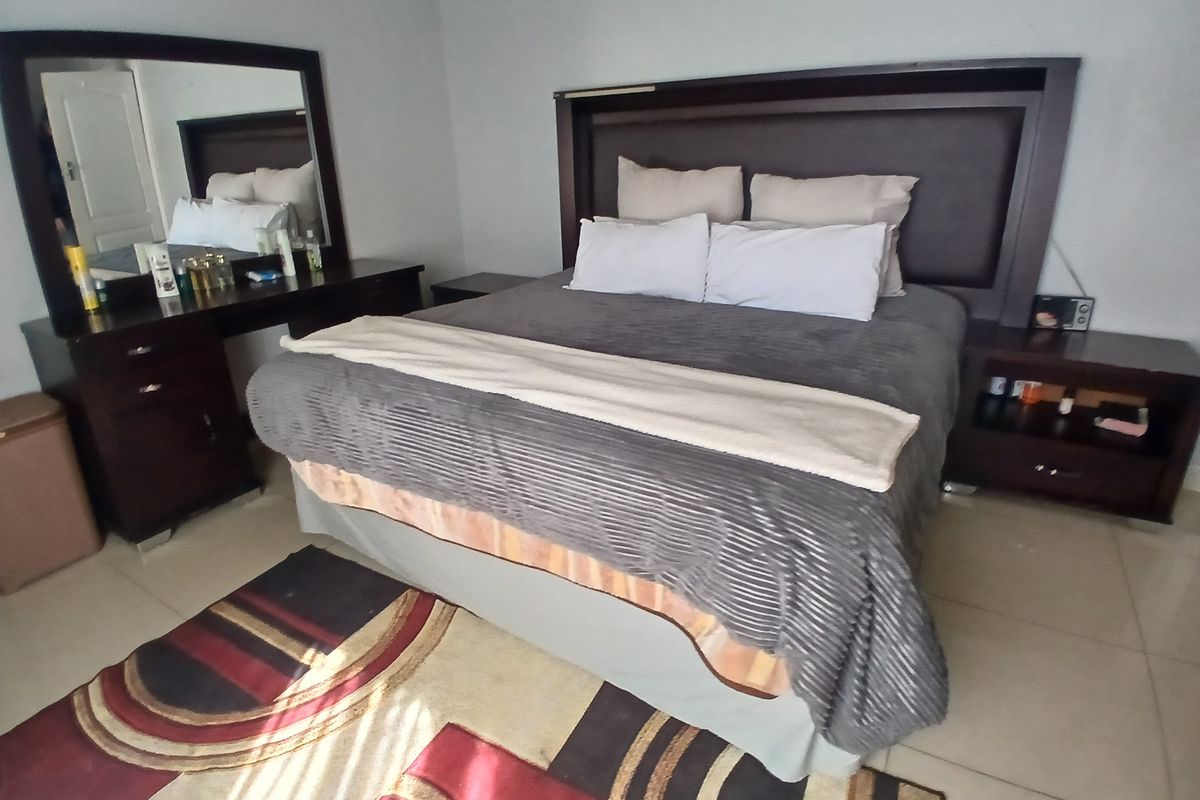 A bedroom featuring tiled flooring and neutral wall finishes, providing a functional space for rest.
