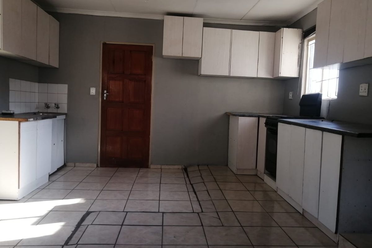 A functional kitchen space featuring built-in cabinetry, tiled flooring, and a built-in oven, offering a blank canvas for potential renovation and modernization.