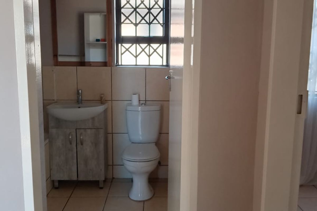 A functional bathroom featuring a vanity cabinet with a basin, a standard toilet, and tiled finishes throughout.