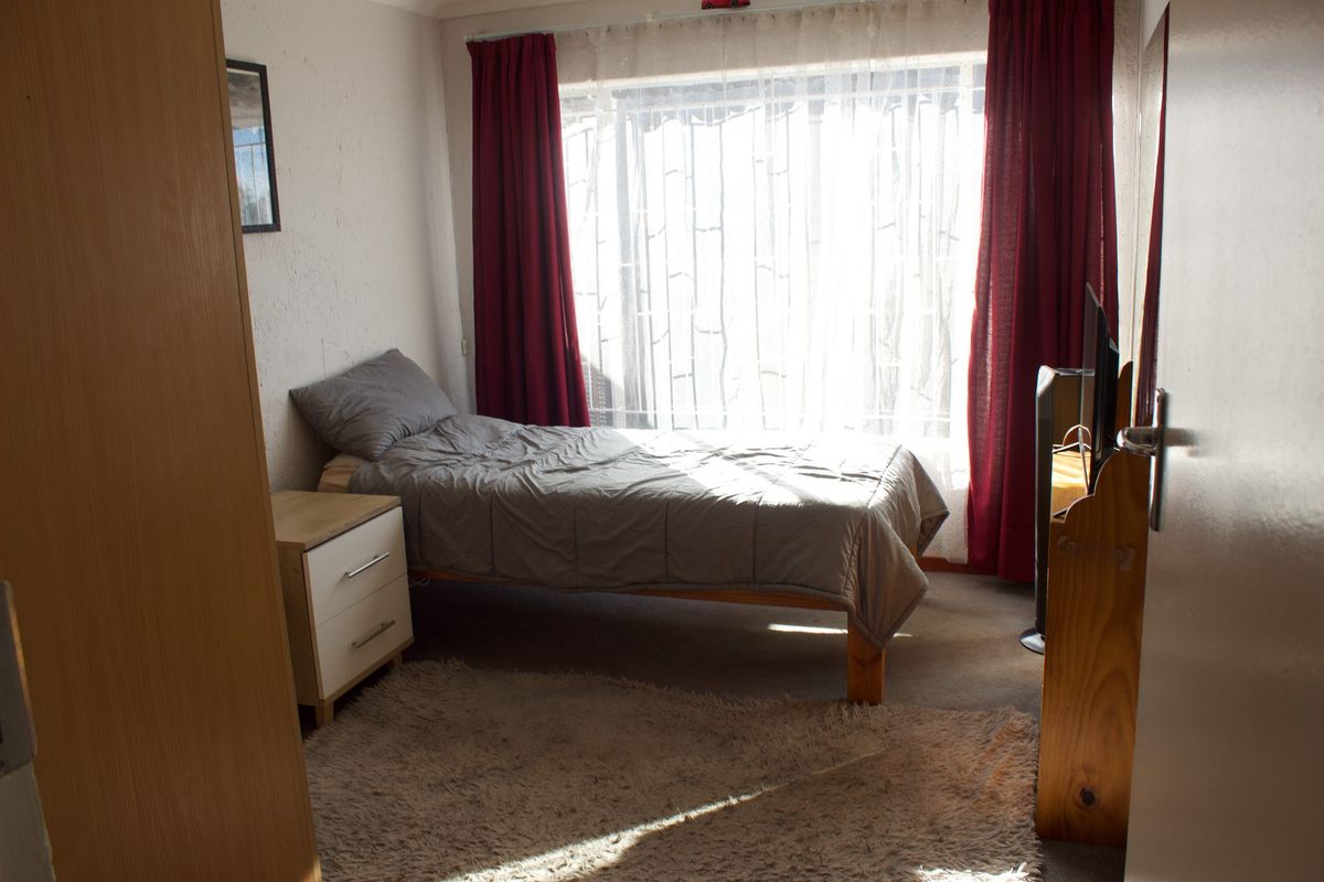 A functional bedroom featuring a large window with natural light and a built-in cupboard for storage.