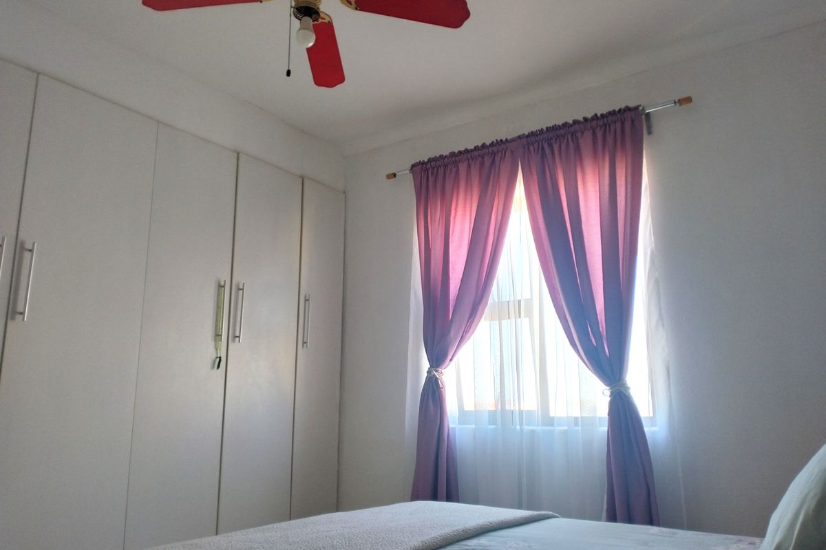 A bedroom featuring built-in floor-to-ceiling wardrobes and a ceiling fan, providing functional storage and climate control.