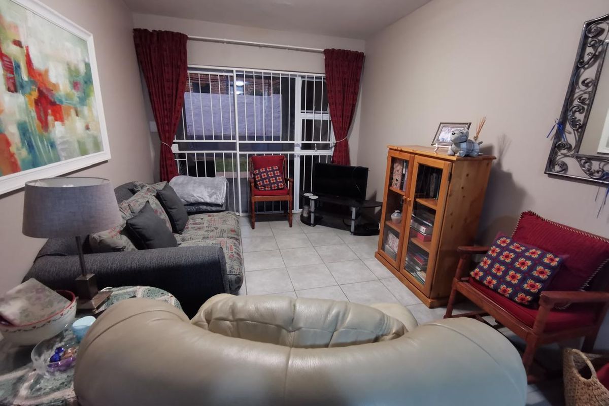 A comfortable living room featuring tiled flooring and a sliding door with integrated security gate, providing access to the exterior.