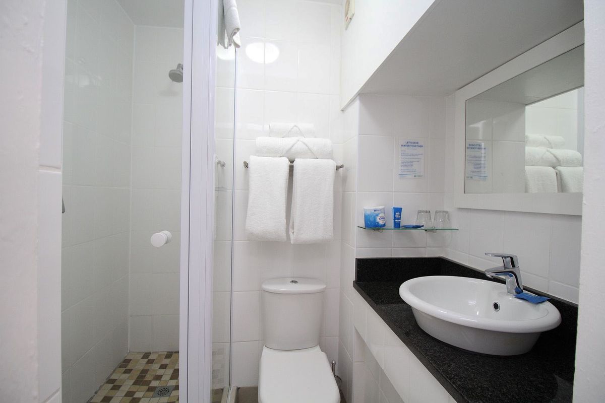 Compact bathroom featuring a white ceramic toilet, a glass-enclosed shower, and a vanity with a black countertop and vessel sink.