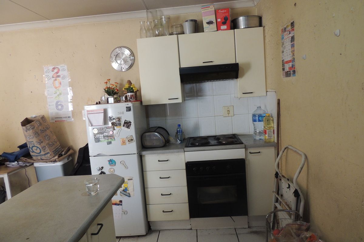 A compact kitchen featuring built-in cabinetry, an electric hob, oven, and extractor fan, requiring cosmetic updates to improve the overall condition.