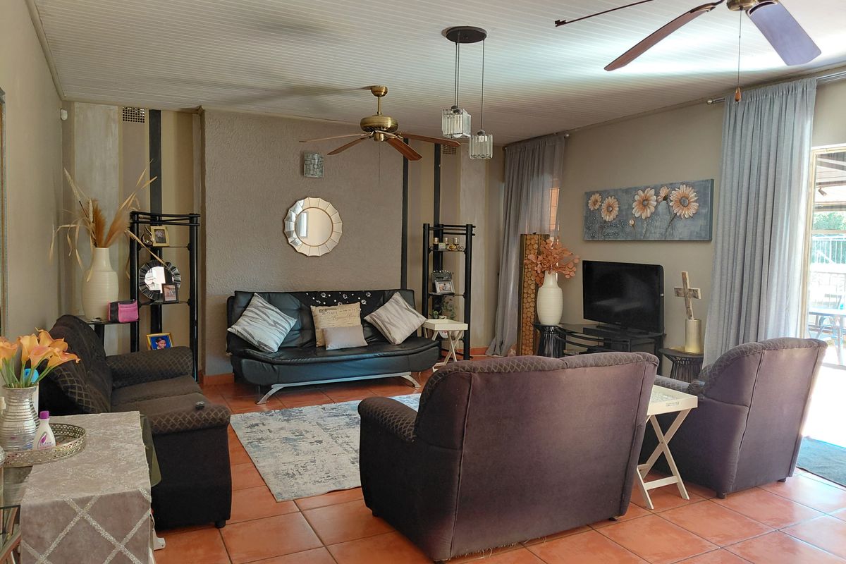 A comfortable living room featuring tiled flooring, a textured feature wall, and a ceiling fan, with direct access to the outdoor area.