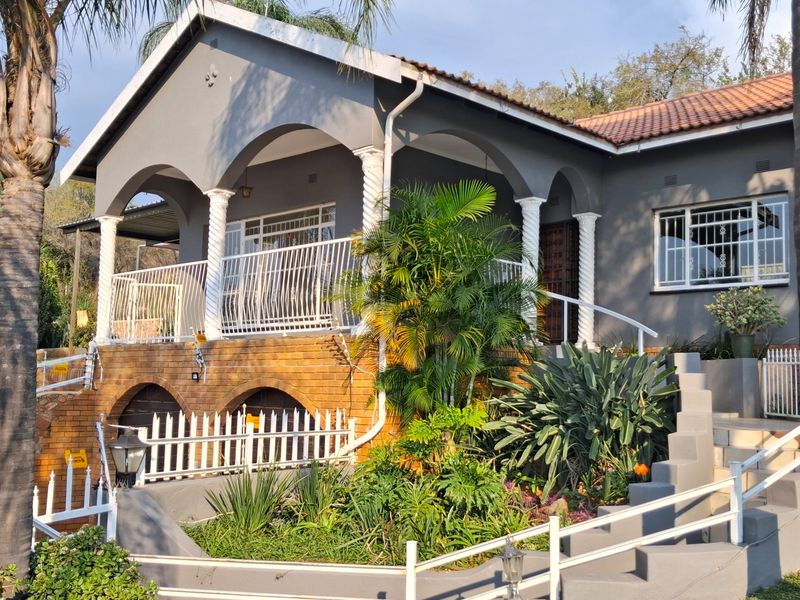 A charming exterior view of the house featuring a covered patio with arched columns, brick base detailing, and a landscaped front garden.