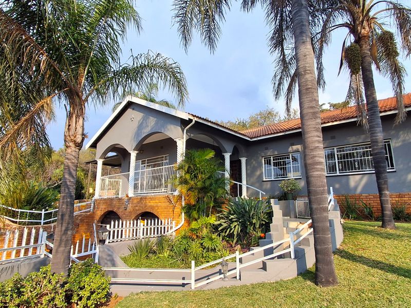 A well-maintained single-story residence featuring a covered front porch, brick base detailing, and established garden landscaping with mature palm trees.