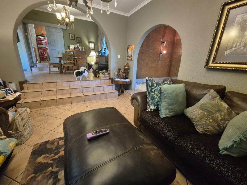 Open plan living area featuring tiled flooring, a raised dining platform, and distinctive arched architectural details connecting the spaces.