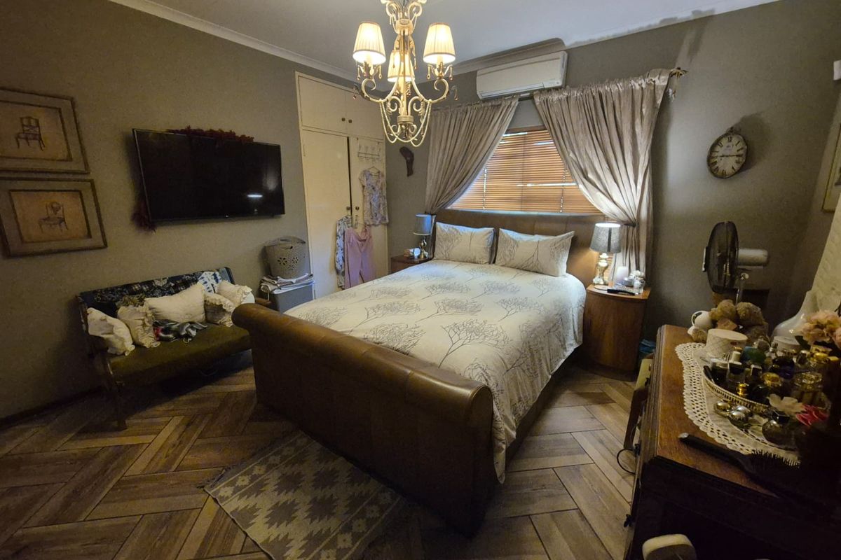 A well-maintained bedroom featuring stylish herringbone flooring, built-in cupboards, and a split-system air conditioner for climate control.