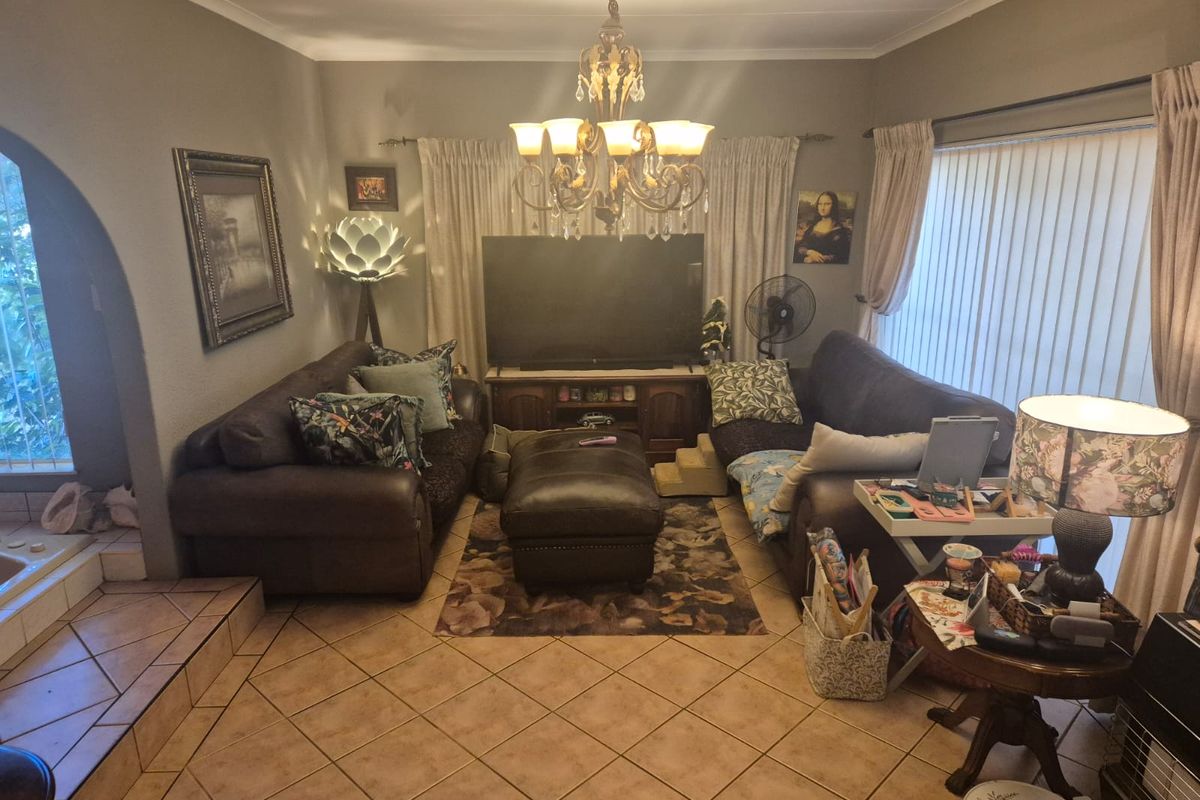 A cozy living room featuring ceramic tile flooring, an arched entryway, and a central chandelier, providing a comfortable and functional family space.