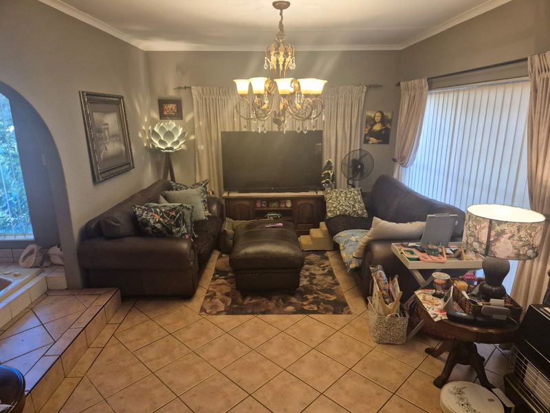 A cozy living room featuring ceramic tile flooring, an arched entryway, and a central chandelier, providing a comfortable and functional family space.