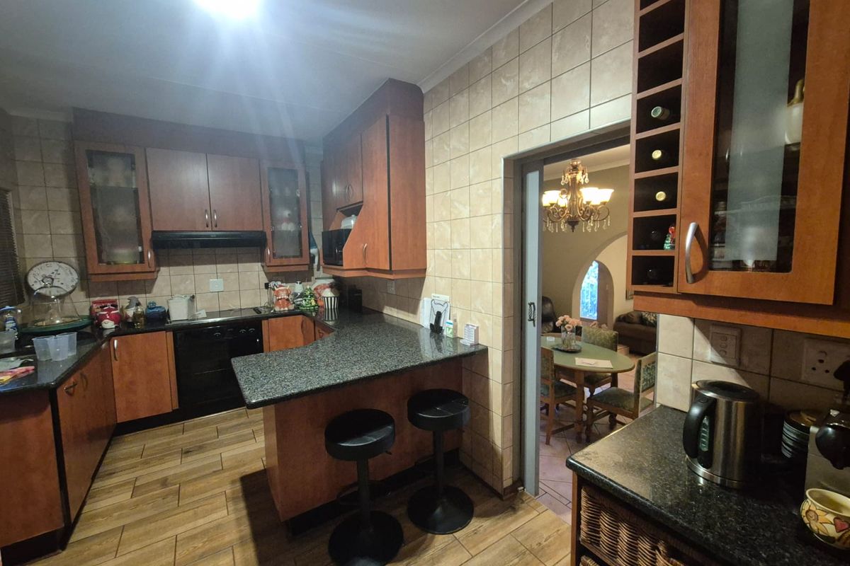 A functional kitchen featuring granite countertops, wood-finish cabinetry, integrated wine storage, and tiled flooring, with a sliding door leading to the dining area.