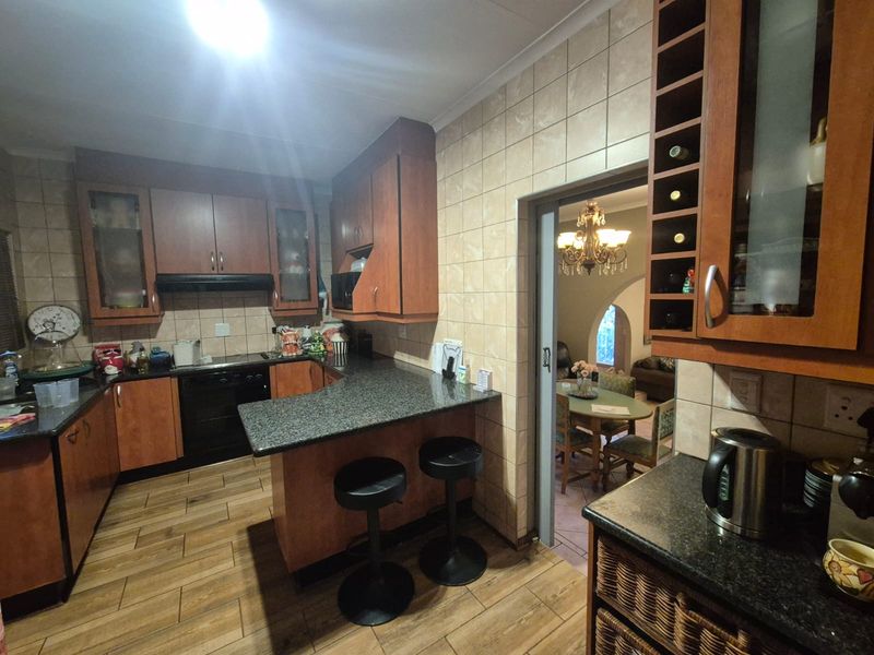 A functional kitchen featuring granite countertops, wood-finish cabinetry, integrated wine storage, and tiled flooring, with a sliding door leading to the dining area.