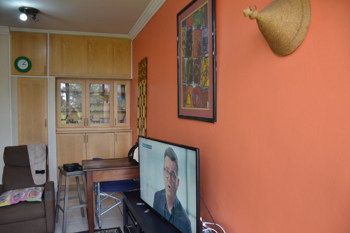 A living room featuring built-in wooden cabinetry, crown molding, and tiled flooring, finished with vibrant orange wall paint.