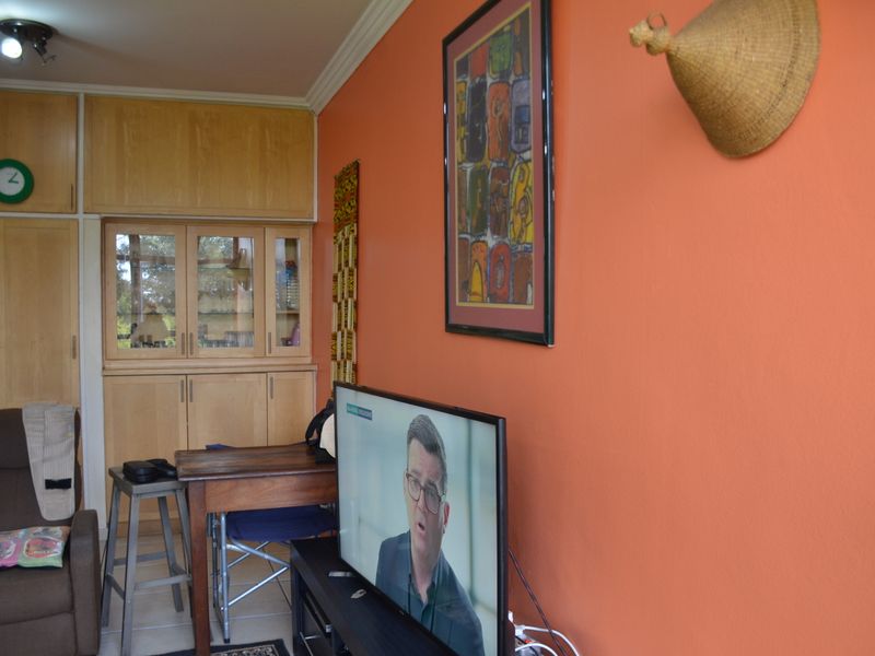 A living room featuring built-in wooden cabinetry, crown molding, and tiled flooring, finished with vibrant orange wall paint.