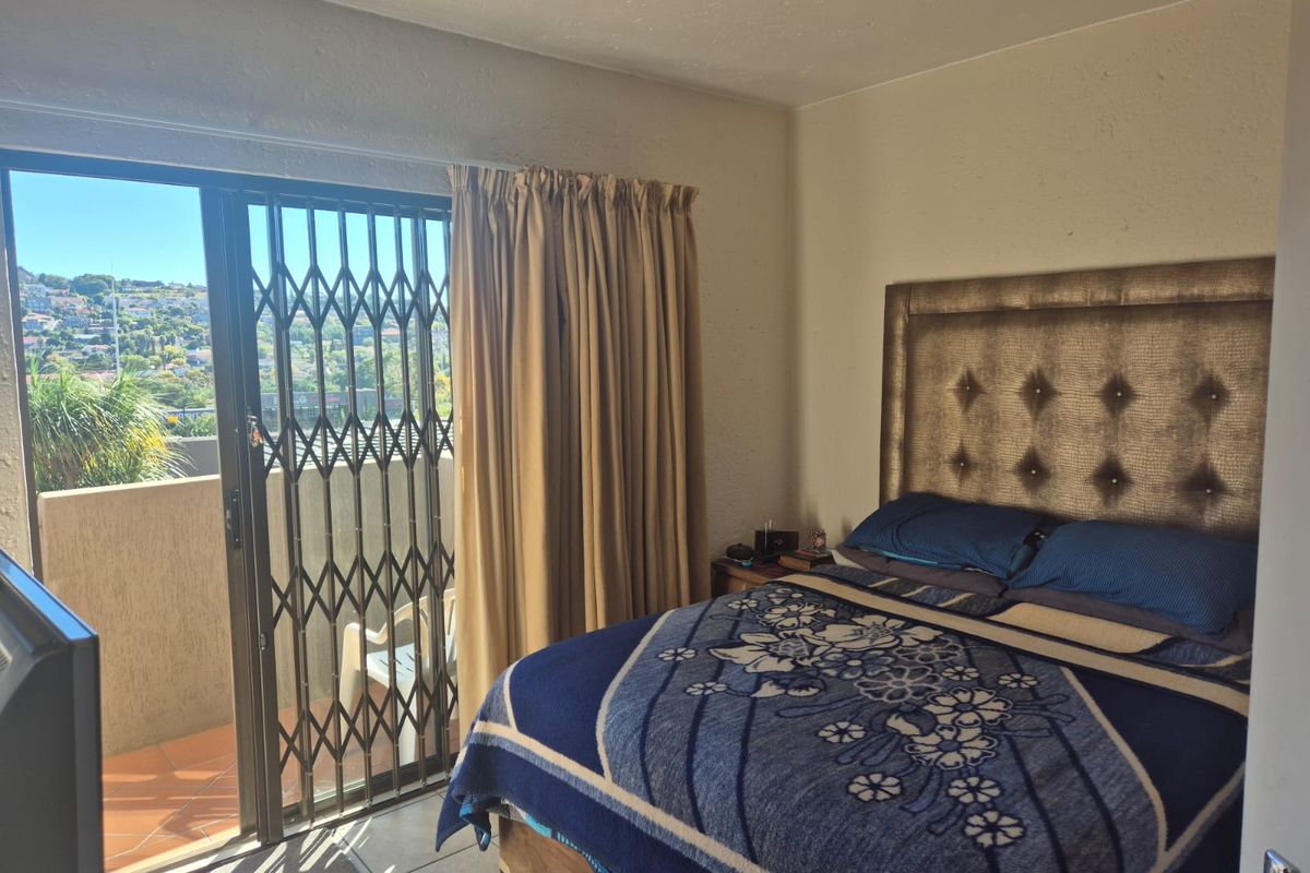 A bedroom featuring tiled flooring and a sliding glass door with a security gate, providing access to an outdoor balcony area.