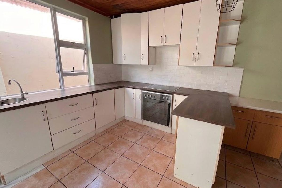 A functional kitchen featuring built-in cabinetry, a built-in oven with electric hob, subway tile backsplash, and tiled flooring under a timber ceiling.
