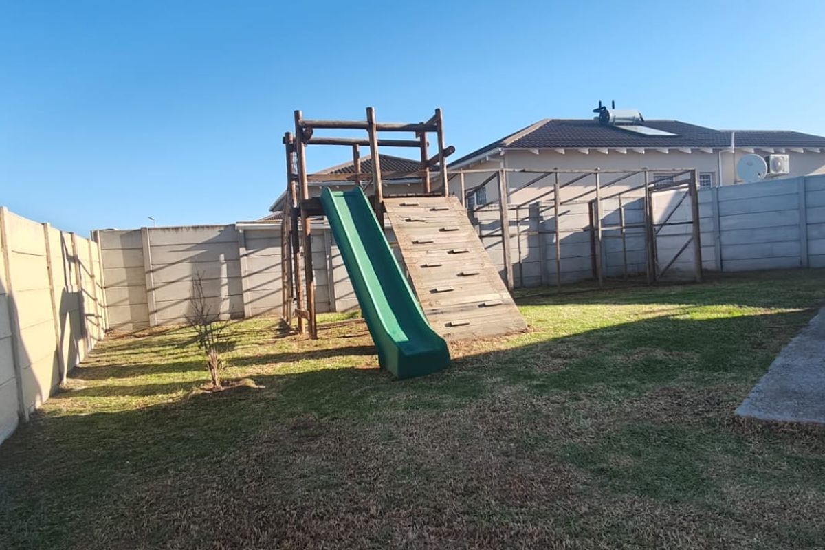 A private rear garden featuring a lawn, concrete patio area, and enclosed by precast concrete boundary walls.