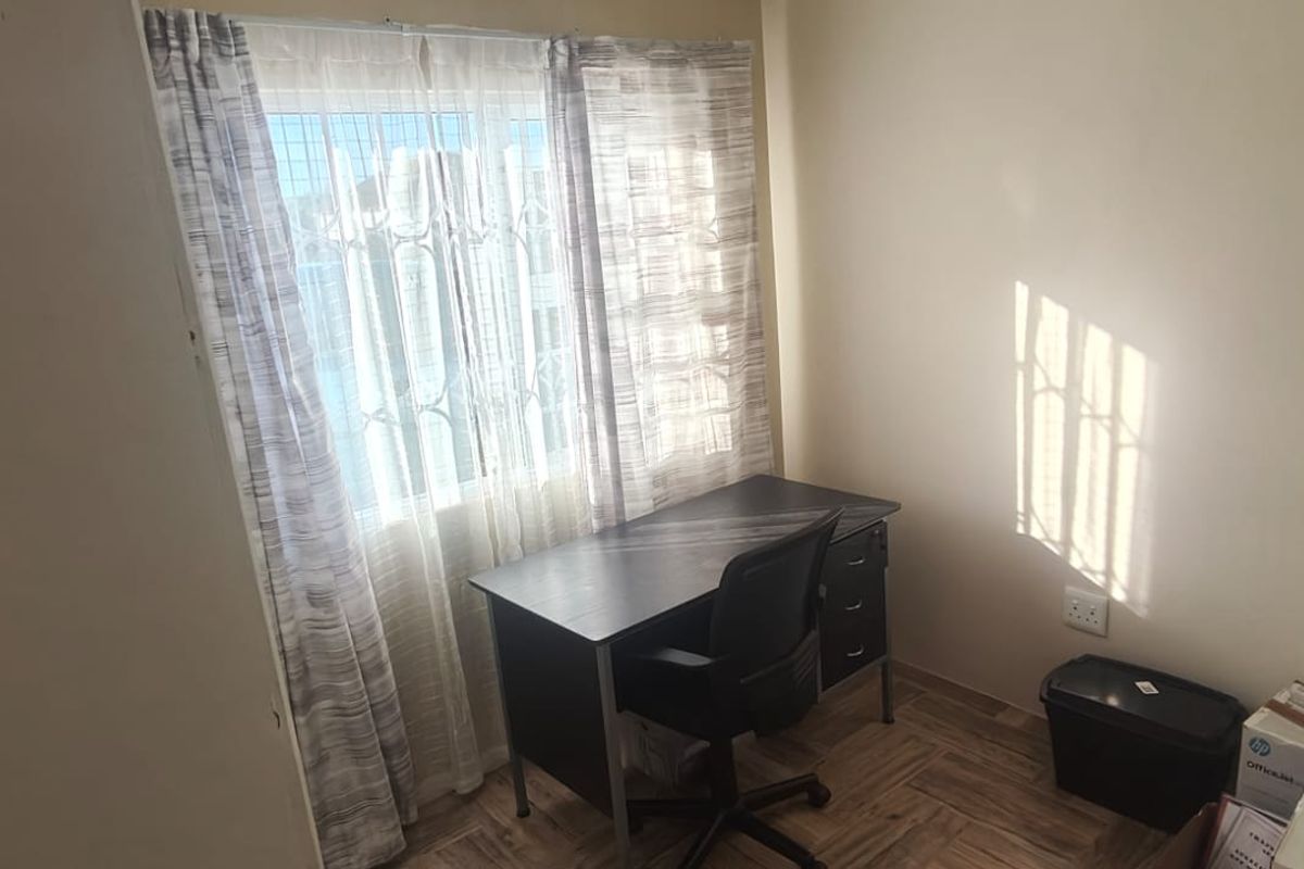 A functional bedroom featuring tiled flooring and a window fitted with a security gate, providing natural light and basic security.