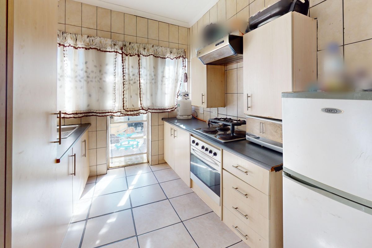A functional kitchen featuring built-in cabinetry, a gas hob, an extractor fan, and tiled finishes, offering a practical layout for daily cooking.