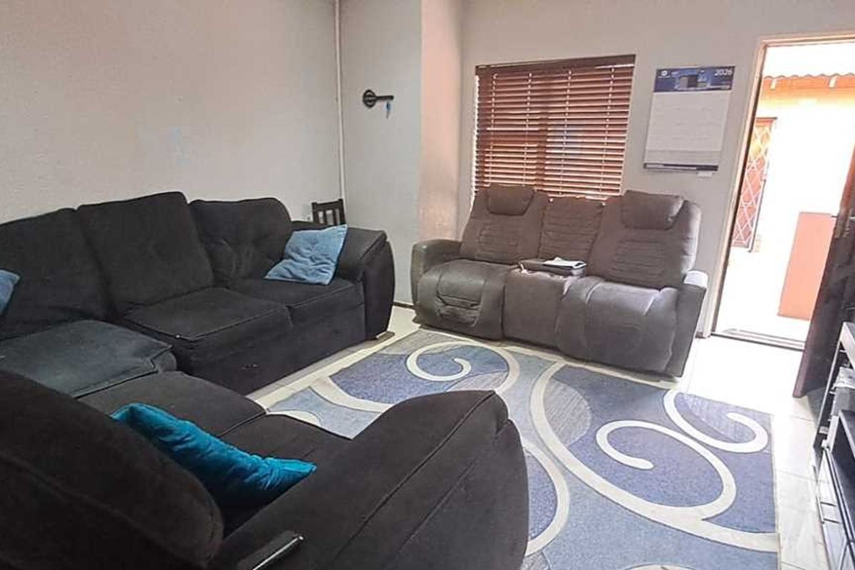A living room area featuring tiled flooring, venetian blinds, and direct access to an outdoor space.