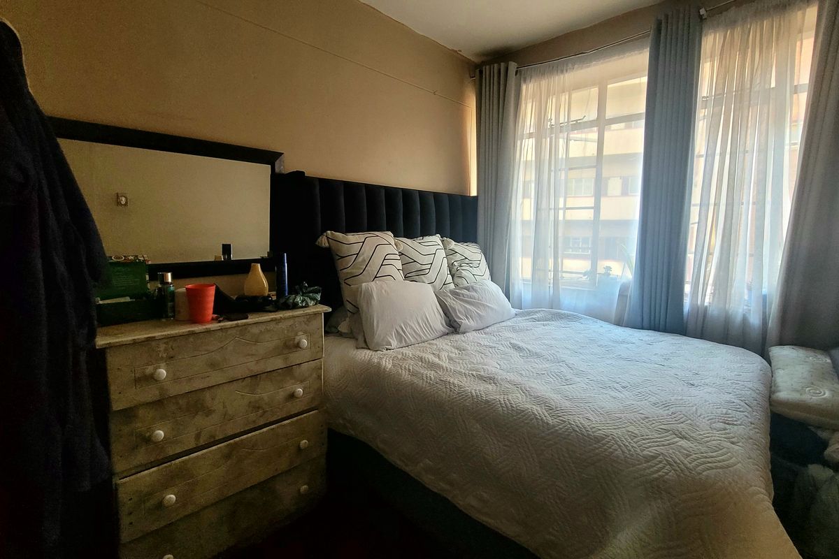 A cozy bedroom featuring natural light through large windows with installed curtain rails, providing a comfortable and functional sleeping space.