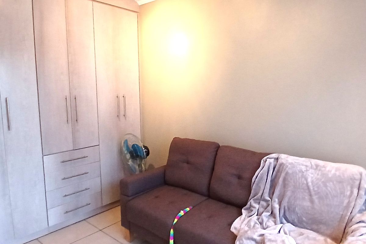 A bedroom featuring light-toned built-in cupboards and tiled flooring, providing functional storage space.