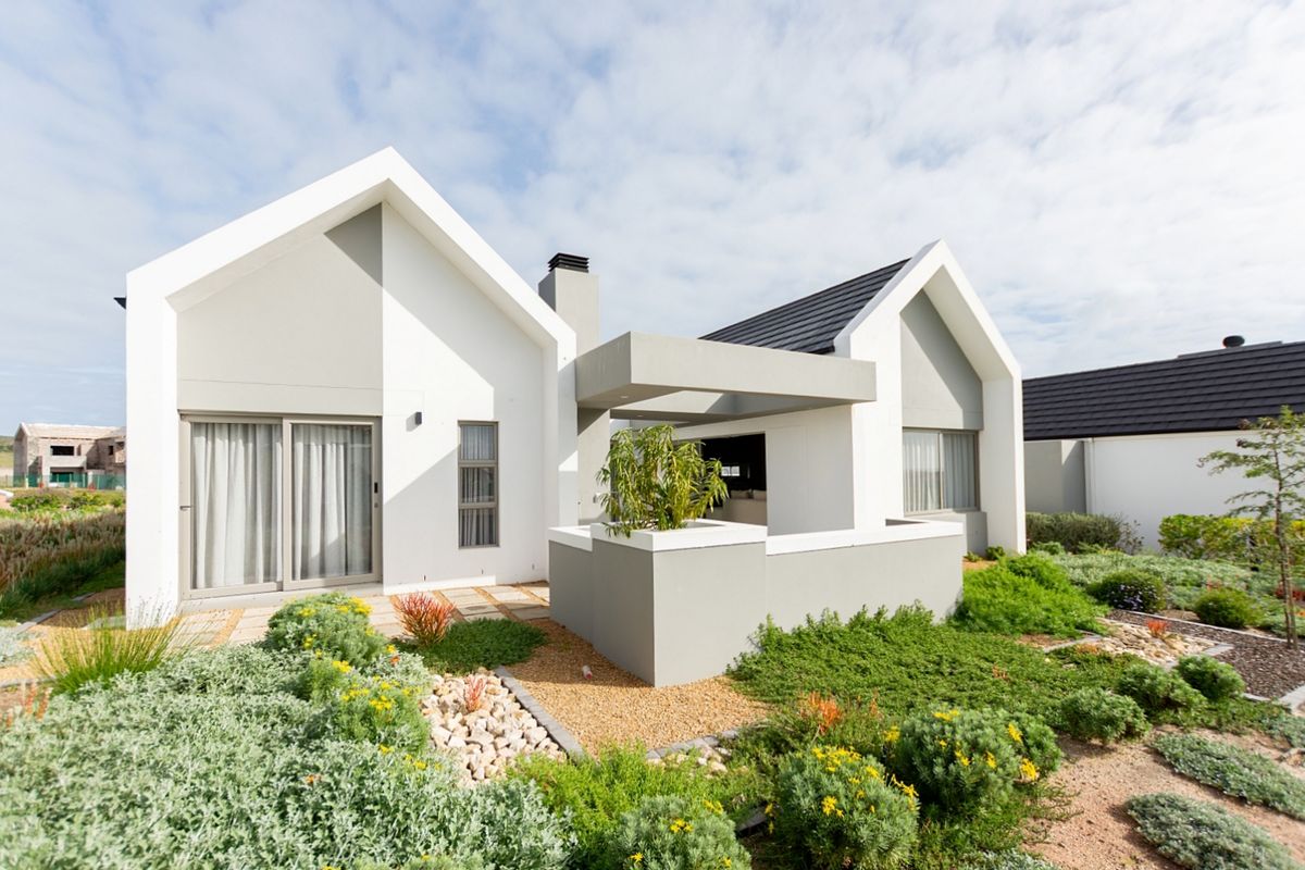 Modern architectural rear elevation featuring a covered patio, clean lines, and a well-maintained landscaped garden.