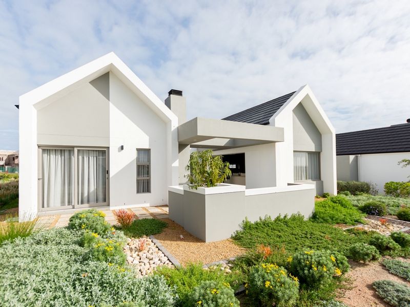 Modern architectural rear elevation featuring a covered patio, clean lines, and a well-maintained landscaped garden.